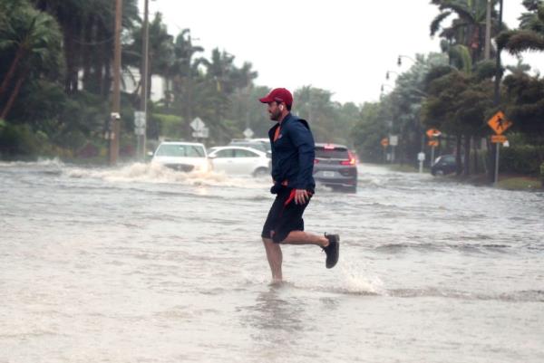 Storm Nicole nears hurricane strength as a man jogs through flooded roads in the Palm Beach area.