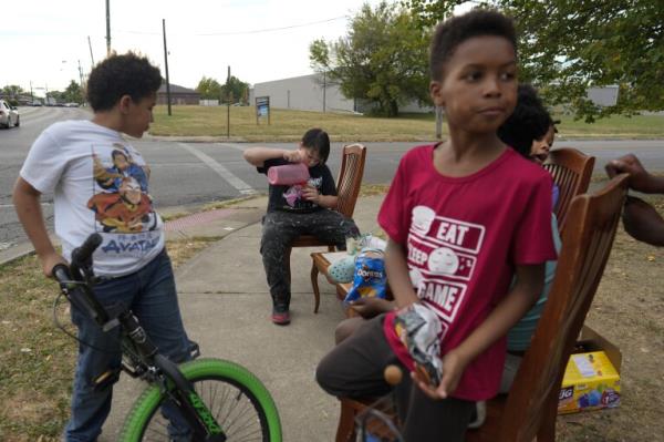 Neighborhood kids gather to sell Kool-Aid and chips, Tuesday, Sept. 17, 2024, in Springfield, Ohio. Some were kept home from school because of the bomb threats at their schools, and if that happens again, they plan to be at the corner with Kool-Aid and chips again tomorrow. (AP Photo/Carolyn Kaster)