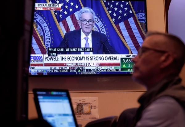 Trader Neil Catania working on the floor of the New York Stock Exchange while a news co<em></em>nference of Federal Reserve Chair Jerome Powell plays on a screen.