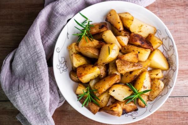 Roasted potatoes with rosemary in a white bowl, pictured from above