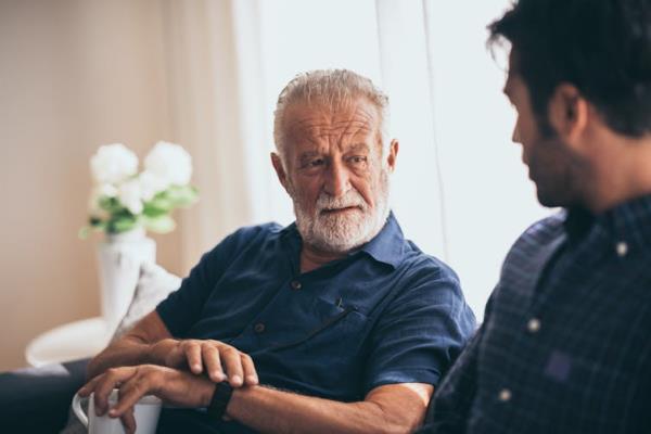 An older man looks serious as he speaks to a younger man.