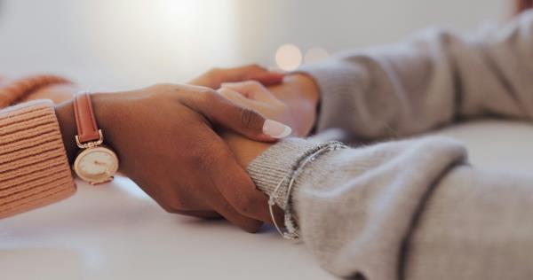 A woman's hands hold another woman's hands.