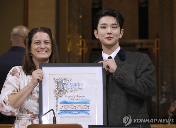 In this Getty Images photo, Joshua (R), a member of the K-pop group Seventeen, holds the certificate of appreciation presented by Katy Yaroslavsky of the Los Angeles City Council at Los Angeles City Hall on Nov. 8, 2024. (Yonhap)