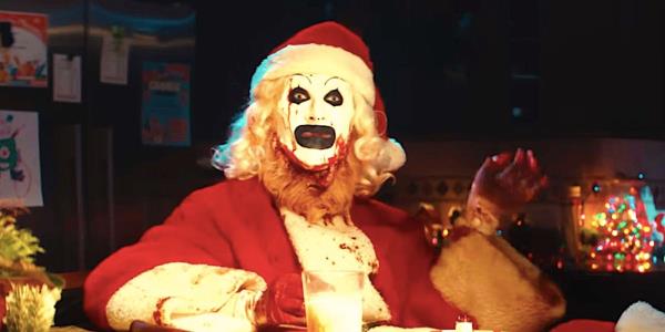 Art the Clown sits at kitchen table dressed as Santa with milk and coo<em></em>kies in Terrifier 3