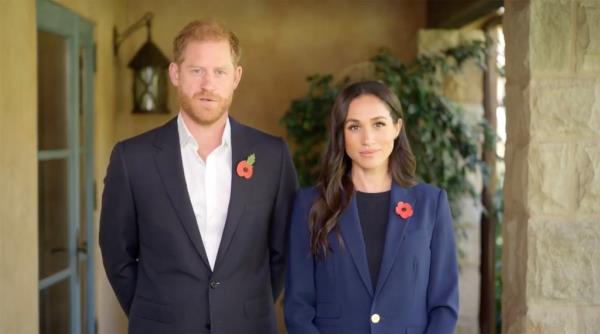 Prince Harry and Meghan Markle standing together, looking stiff, at a public appearance representing a crossroads in their work